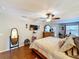Bright main bedroom featuring wood floors, ceiling fan, mounted TV, and dressing mirror at 1011 Dampierre Ct, Kissimmee, FL 34759