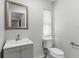 Bright bathroom features a gray vanity, toilet, updated fixtures and a large mirror at 1024 Cohassett Ave, Lake Wales, FL 33853