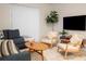 Comfortable living room featuring a plush sofa, two cream-colored chairs, a natural wood coffee table, and a large TV at 1160 Kingsbarn St, Davenport, FL 33896