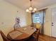Cozy dining room features a wooden table set, decorative chandelier, and natural light from the window at 143 Piedmont Park Ave, Davenport, FL 33897