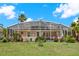 Beautifully landscaped backyard with a screened-in pool, lush greenery, and serene views of the surrounding landscape at 1560 The Oaks Blvd, Kissimmee, FL 34746