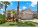 Beautiful home with mature landscaping, flowering plants, a two-car garage and neutral paint at 1560 The Oaks Blvd, Kissimmee, FL 34746