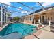 Lushly landscaped backyard with an enclosed pool area, an inviting spa, a water feature, and ample seating at 1560 The Oaks Blvd, Kissimmee, FL 34746