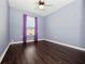 Bedroom featuring wood floors, a ceiling fan, light-blue walls and window with violet curtains at 1917 Compass Flower Way, Ocoee, FL 34761