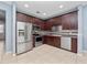 Well-equipped kitchen with stainless steel appliances, cherry cabinets, and neutral tile floors at 1917 Compass Flower Way, Ocoee, FL 34761