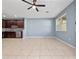 Spacious living area with neutral tile flooring, ceiling fan and partial view of kitchen appliances at 1917 Compass Flower Way, Ocoee, FL 34761