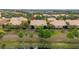 Scenic aerial view of a well-maintained residential community with lush landscaping and tile roofs near a pond at 2376 Palm Tree Dr, Kissimmee, FL 34759