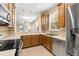 Well-lit kitchen featuring stainless steel appliances and wooden cabinetry with views to the living area at 2376 Palm Tree Dr, Kissimmee, FL 34759