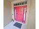 Bright pink front door with sidelights and transom window, features a 'welcome' mat and charming decor at 2531 Old Kent Cir, Kissimmee, FL 34758