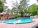 Community pool surrounded by mature trees and a brick pool deck is perfect for relaxation at 2864 N Powers Dr # 150, Orlando, FL 32818