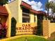 Charming entrance to Oak Shadows Condominiums, featuring lush landscaping and attractive signage at 2864 N Powers Dr # 150, Orlando, FL 32818