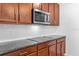 Close-up of a kitchen showcasing granite countertops, stainless steel microwave and cooktop, and wood cabinets at 2922 Crest Dr, Kissimmee, FL 34744