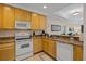 Functional kitchen with white appliances, wood cabinets, and a view to the dining and living spaces at 3060 Pirates Retreat Ct # 309, Kissimmee, FL 34747