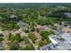 An aerial view of a home nestled among trees with a view of a pond and a nearby commercial area at 308 Forest St, Fruitland Park, FL 34731