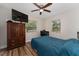 Cozy bedroom features a ceiling fan, hardwood floors, a window, a wardrobe, and a television at 308 Forest St, Fruitland Park, FL 34731