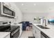Contemporary kitchen with stainless steel appliances, quartz countertops, and adjacent living area at 3575 Landing Net Dr, Kissimmee, FL 34746