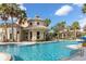 Beautiful community pool featuring a circular design, palm trees, and a clubhouse in a tropical setting at 3575 Landing Net Dr, Kissimmee, FL 34746