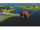 Aerial view of a community boat dock house beside a lake, surrounded by lush greenery and picturesque residences at 3881 Shoreside Dr, Kissimmee, FL 34746