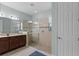 Bathroom featuring walk-in shower with glass doors, vanity with dual sinks, and tiled flooring at 3881 Shoreside Dr, Kissimmee, FL 34746