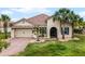 Charming home featuring a brick driveway, arched entry, and well-maintained landscaping and an attached two-car garage at 3881 Shoreside Dr, Kissimmee, FL 34746