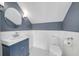 Bathroom featuring a blue vanity with marble top, a round mirror, and white wainscoting at 423 Arbor Cir, Celebration, FL 34747