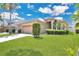 Well-maintained single-Gathering home with a green lawn, two-car garage, and manicured landscaping at 5114 Olde Kerry Dr, Orlando, FL 32837