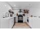 Modern kitchen with white cabinets, quartz countertops, stainless steel appliances, and charming open shelving at 5234 Eaglesmere Dr # D04, Orlando, FL 32819