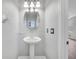 Powder room featuring an oval mirror and pedestal sink with white walls and light fixtures at 5768 Los Palma Vista Dr, Orlando, FL 32837