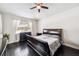 Bedroom features dark hardwood floors, ceiling fan, and bright window dressed in sheer patterned curtains at 6080 Fender Ct, Orlando, FL 32837