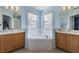 Primary bath with tub, double sinks, wood cabinets and bright blue walls at 8571 La Isla Dr, Kissimmee, FL 34747