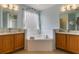 Primary bath with tub, double sinks, wood cabinets and bright blue walls with transom window at 8571 La Isla Dr, Kissimmee, FL 34747