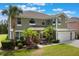 Inviting two-story home with a three-car garage, lush tropical landscaping, and a well-manicured lawn at 8571 La Isla Dr, Kissimmee, FL 34747