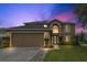 Charming two-story home with a well-manicured lawn and two car garage at dusk at 102 Royalty Cir, Sanford, FL 32771