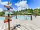 Community pool with tropical plants, a sign with mileage to other cities, lounge chairs and umbrellas at 1067 Plantation Ln, Davenport, FL 33896