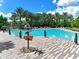 Large community pool with brick patio, palm trees, lounge chairs, tropical decorations and a sign with mileage to other cities at 1067 Plantation Ln, Davenport, FL 33896