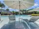 Lounge chairs and umbrellas at a community pool surrounded by palm trees and other tropical plants at 1067 Plantation Ln, Davenport, FL 33896