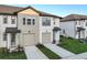 Charming townhome featuring a garage, blue front door, and manicured lawn in a modern community at 1067 Plantation Ln, Davenport, FL 33896
