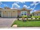 Charming villa featuring stone accents, a two-car garage, and well-maintained landscaping under a sunny, partly cloudy sky at 1082 Blackwolf Run Rd, Davenport, FL 33896