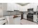 Stylish kitchen with white cabinets, stainless steel appliances, a breakfast bar, and neutral countertops and backsplash at 1082 Blackwolf Run Rd, Davenport, FL 33896