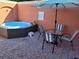 A luxurious patio featuring a modern hot tub and a dining set with striped chairs under a striped umbrella at 153 Pompano Beach Dr Dr, Kissimmee, FL 34746