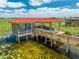 A screened dock with a red tile roof holds a boat covered in a tarp with a walkway out to the dock at 1654 Marina Lake Dr, Kissimmee, FL 34744
