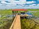 Close-up view of a boat secured in a covered dock with a red tile roof, set on a tranquil lily pad filled lake at 1654 Marina Lake Dr, Kissimmee, FL 34744