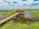 Picturesque dock extending over a lily-covered lake, complete with a covered boathouse featuring a red tile roof at 1654 Marina Lake Dr, Kissimmee, FL 34744