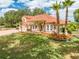 A full exterior of this stucco home with a tile roof, surrounded by a green lawn and mature palm trees at 1654 Marina Lake Dr, Kissimmee, FL 34744