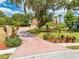 A front exterior of this home with an expansive brick driveway, beautiful landscaping, and a mature shade tree at 1654 Marina Lake Dr, Kissimmee, FL 34744