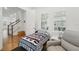 A bedroom with a twin bed, two windows, a grey chair, and access to the hallway and stairs at 1850 Treasure Cv, Celebration, FL 34747