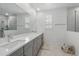 Bright bathroom with double sinks, a large mirror, and a glass-enclosed shower with marble-look tile at 1850 Treasure Cv, Celebration, FL 34747