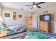 Vibrant bedroom with unique bedding, a ceiling fan, and a dresser with a mounted TV at 214 Tupelo Cir, Davenport, FL 33897