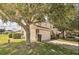Two-story home with a well-manicured lawn, a stone-accented facade, and mature trees creating a shaded area at 214 Tupelo Cir, Davenport, FL 33897