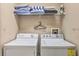 A functional laundry room with a washer, dryer, shelves for linens, and an ironing board at 214 Tupelo Cir, Davenport, FL 33897